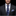 Man wearing a dark suit with a blue paisley tie and matching pocket square on a black background