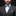Man wearing a gray suit with a blue bow tie and pocket square on a black background