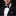Man wearing a black suit with a patterned bow tie and pocket square against a dark background
