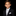 Young boy in a formal black suit with a white shirt and gray tie on a black background