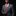 Man wearing a gray suit with a red tie and pocket square on a black background