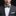 Man wearing a gray suit with a colorful bow tie against a black background