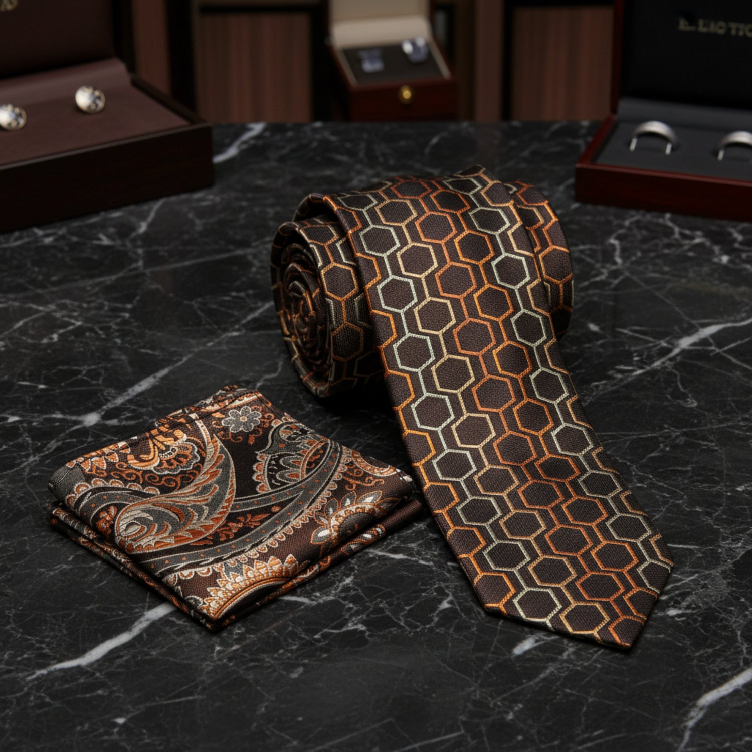 A men's necktie and pocket square set on a white background. The necktie features a dark brown base with a geometric pattern of orange, beige, and light green hexagons.