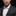 Man wearing a gray suit with a white shirt and green striped pocket square on a black background