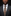 Man wearing a dark suit with a patterned tie and pocket square against a black background