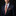 Man wearing a dark suit with a patterned tie and pocket square on a black background
