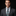 Man wearing a gray suit with a patterned tie against a black background