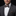 Man wearing a gray suit with a polka dot bow tie and pocket square on a black background