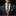 Man wearing a dark suit with a patterned tie and pocket square against a black background