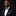 Man wearing a black suit with a green bow tie and pocket square on a dark background