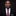 Man wearing a black suit with a red patterned tie against a dark background