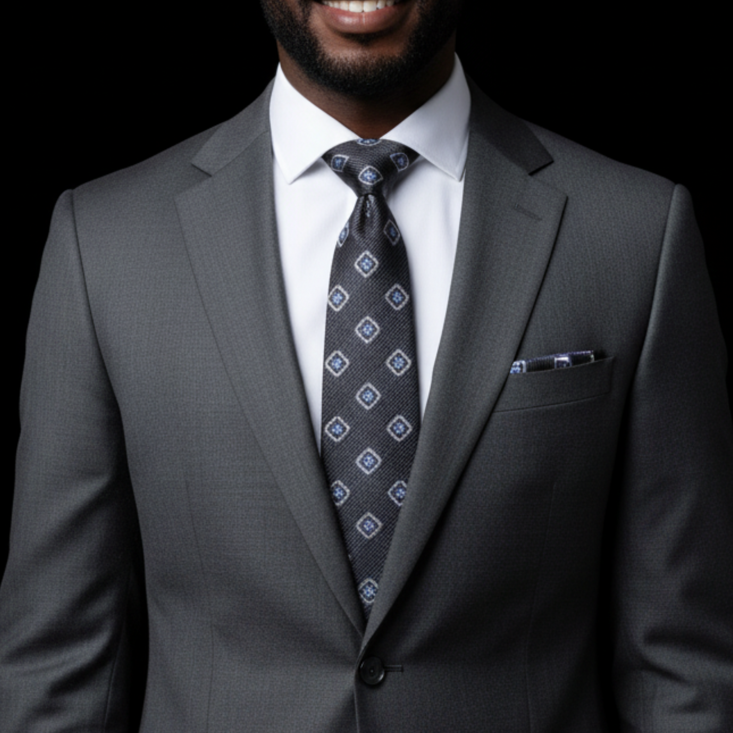 Man wearing a gray suit with a patterned tie on a black background