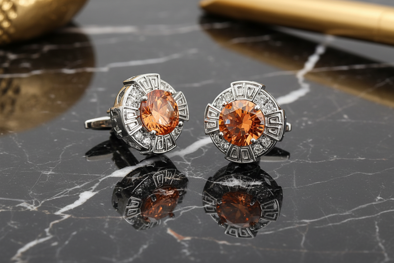 A pair of gold-colored circular cufflinks with red and clear stones set within.