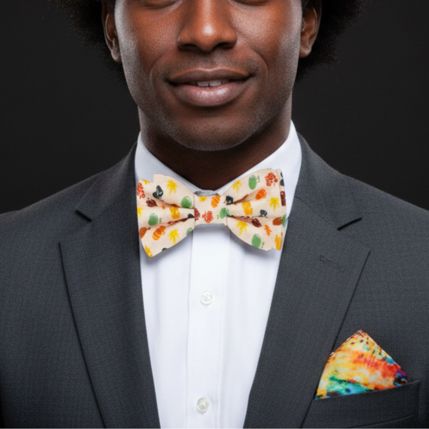 Man wearing a dark suit with a colorful bow tie and pocket square against a black background