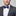 Man wearing a gray suit with a blue bow tie and pocket square on a light gray background