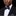 Man wearing a black suit with a blue bow tie and matching pocket square on a black background