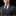 Man wearing a gray suit with a striped tie and pocket square on a black background