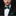 Man wearing a black suit with a green bow tie and matching pocket square on a black background
