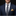 Man wearing a navy suit with a patterned tie and pocket square against a black background