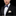 Man wearing a black tuxedo with a blue bow tie and white pocket square on a black background