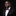 Man wearing a black suit with a red bow tie and pocket square on a black background