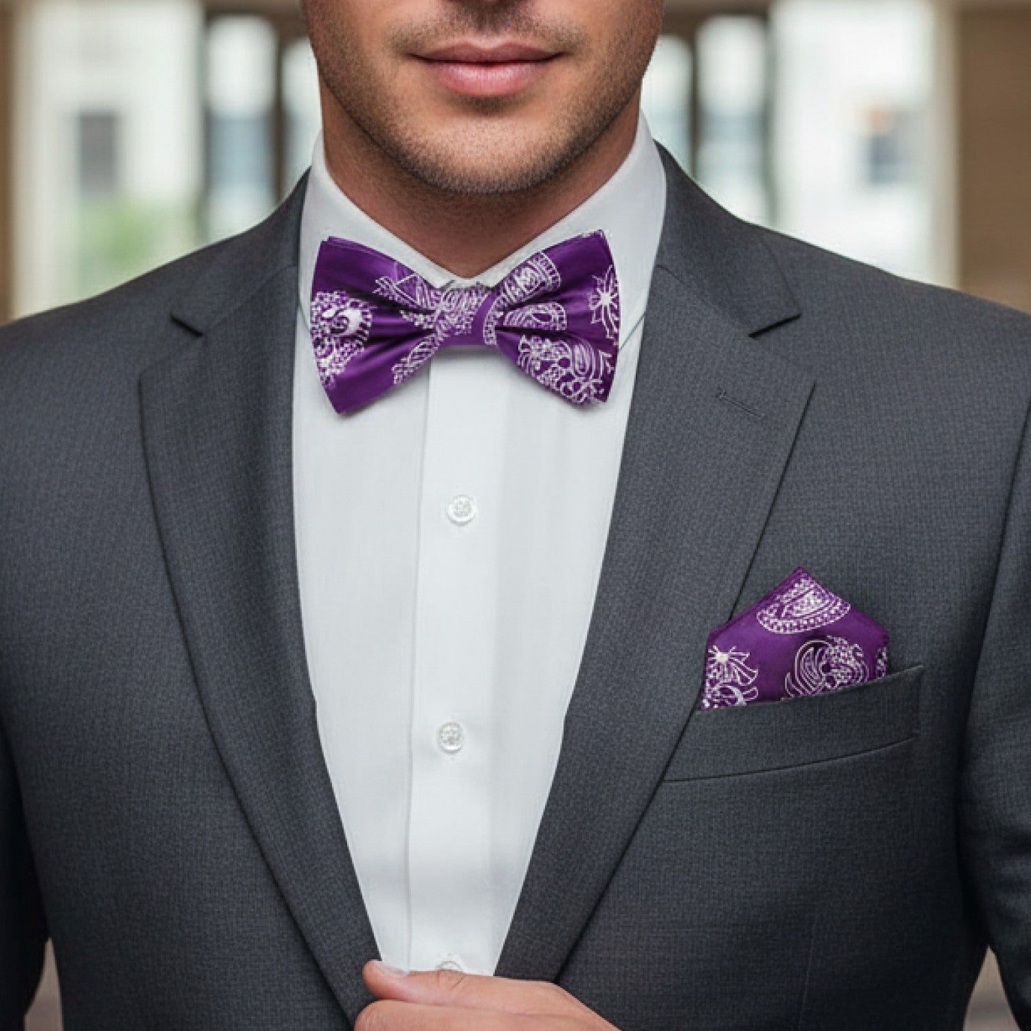 Man wearing a gray suit with a purple bow tie and pocket square.