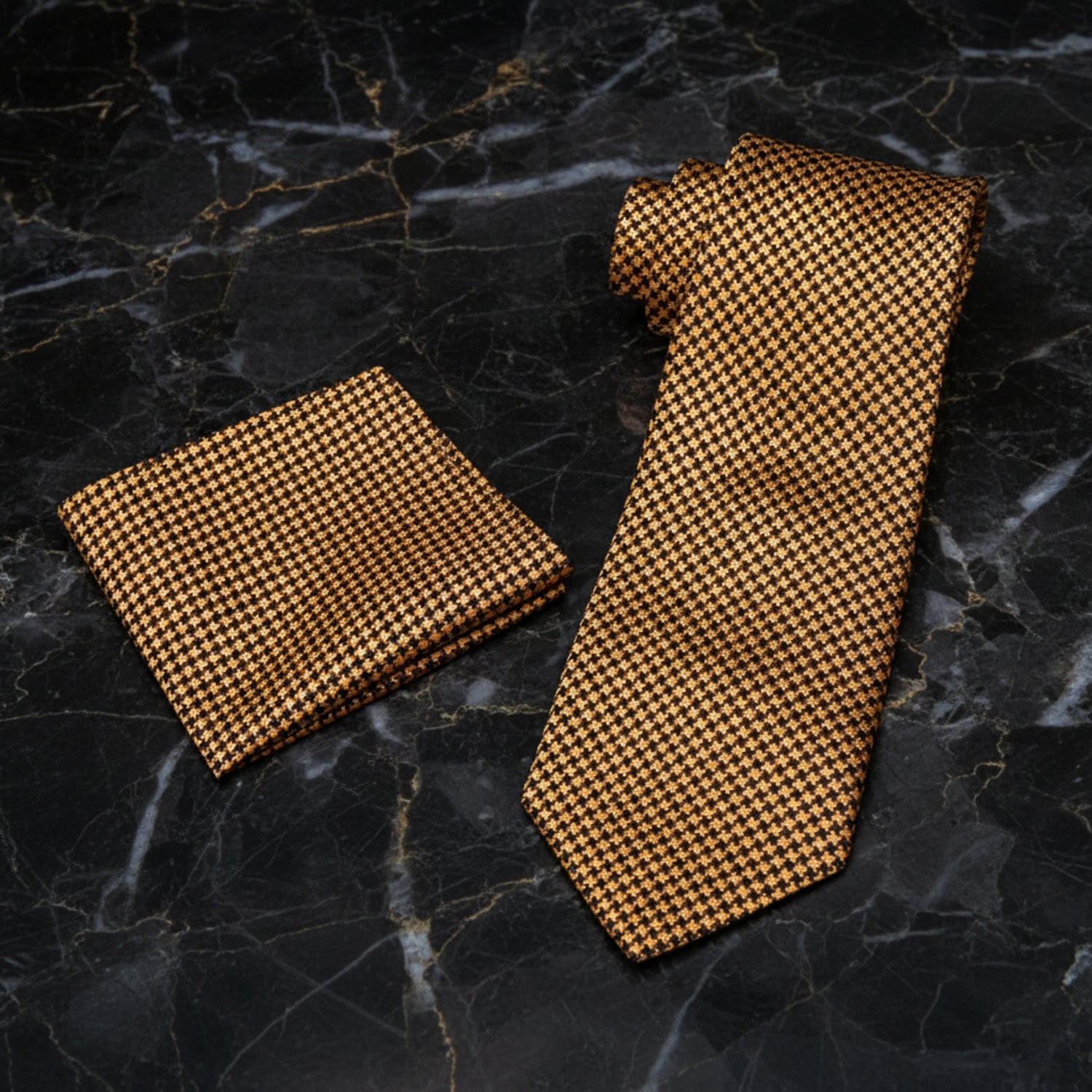 A matching necktie and pocket square set with a small-scale brown and tan houndstooth pattern, displayed on a clean white background.