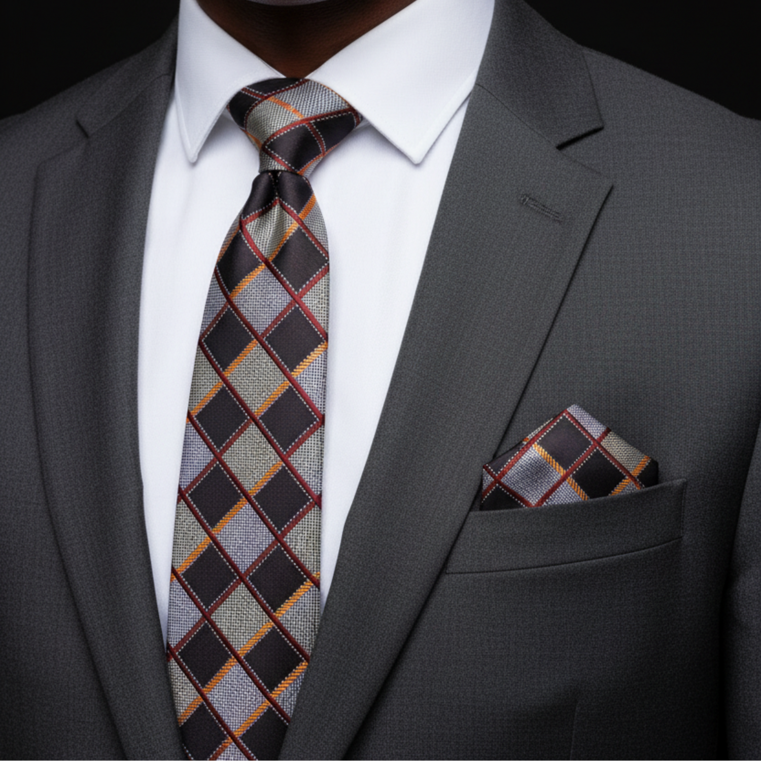 Gray suit with plaid tie and pocket square on a black background