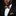 Man wearing a black suit with a gold bow tie and pocket square on a dark background