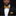 Man wearing a black suit with a yellow bow tie and pocket square against a dark background