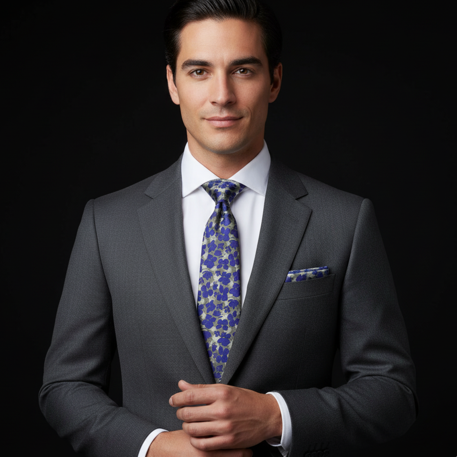 Man wearing a gray suit with a blue floral tie against a black background