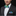Man wearing a black suit with a colorful bow tie and pocket square on a black background