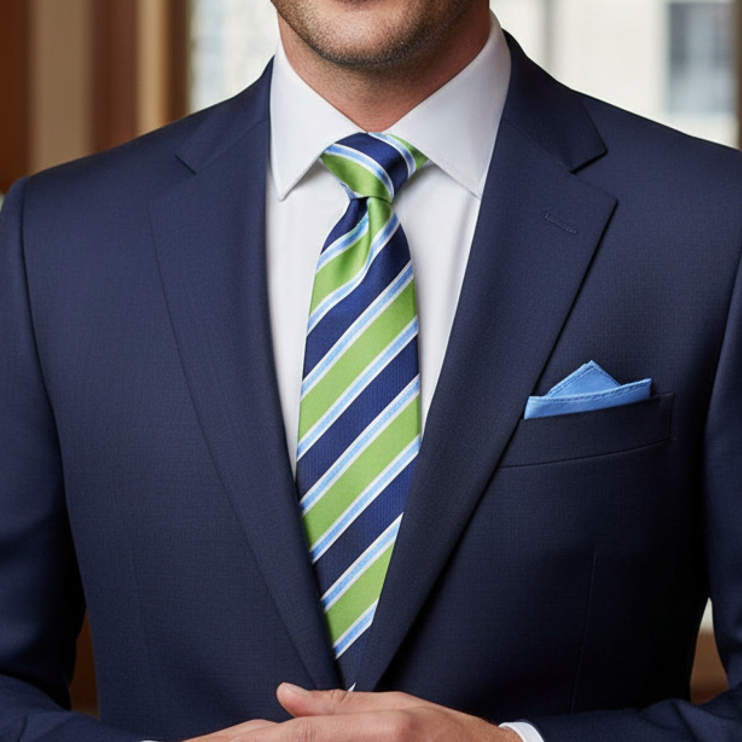 Man wearing a navy suit with a green and blue striped tie and blue pocket square.