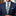 Man wearing a navy suit with a green and blue striped tie and blue pocket square.