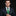 Man wearing a dark suit with a green tie and pocket square on a black background