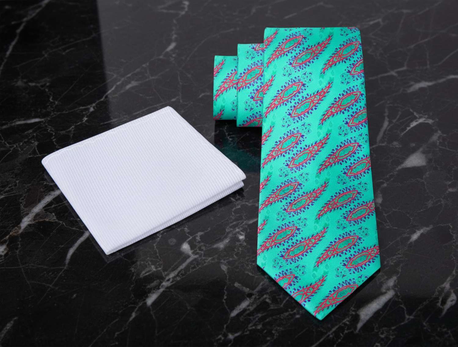 Turquoise tie with pink and purple pattern and white pocket square on a white background