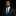 Man wearing a dark suit with a green polka dot thin tie and pocket square on a black background
