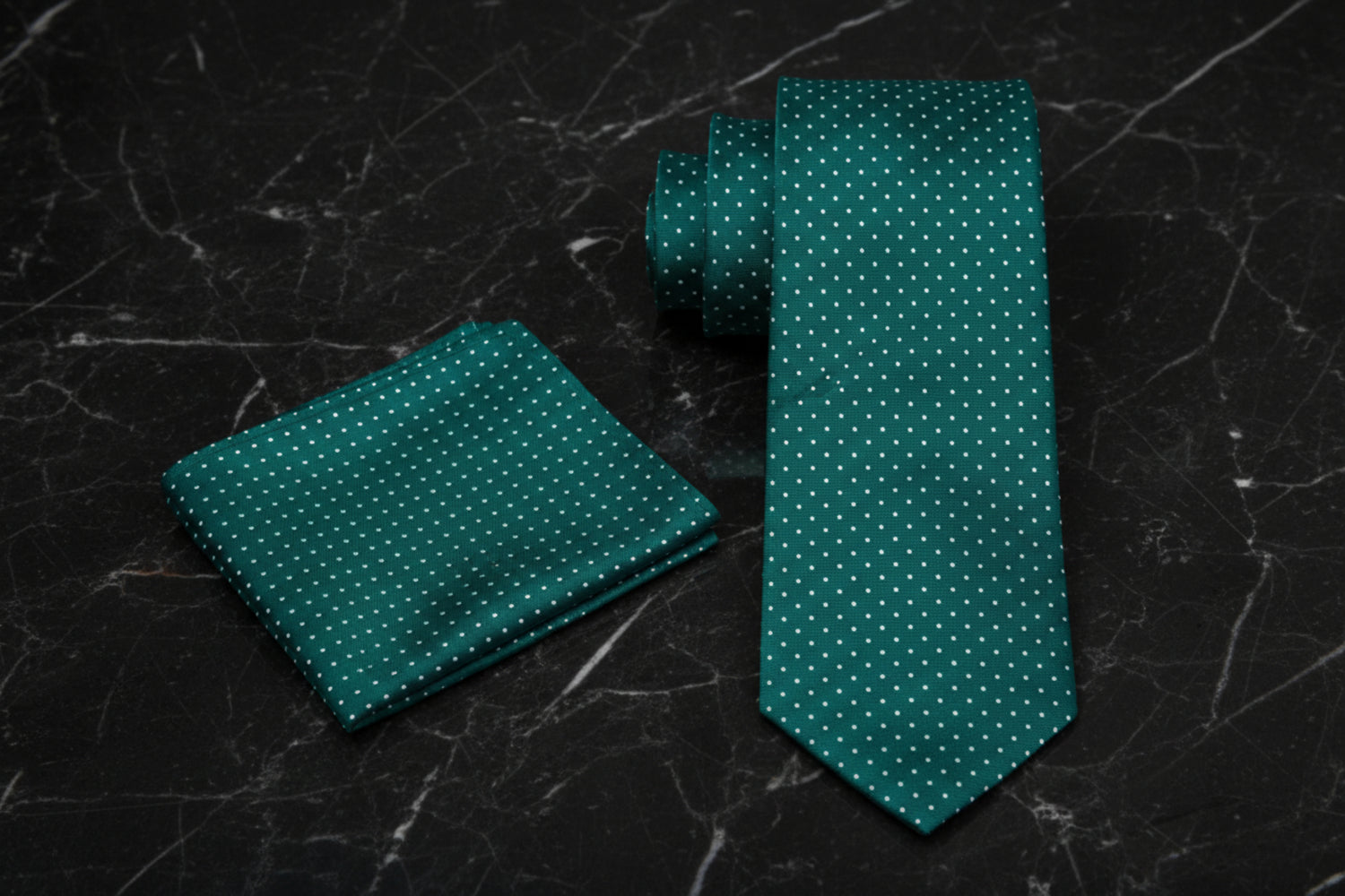 Green polka tie and matching pocket square on a dark textured surface