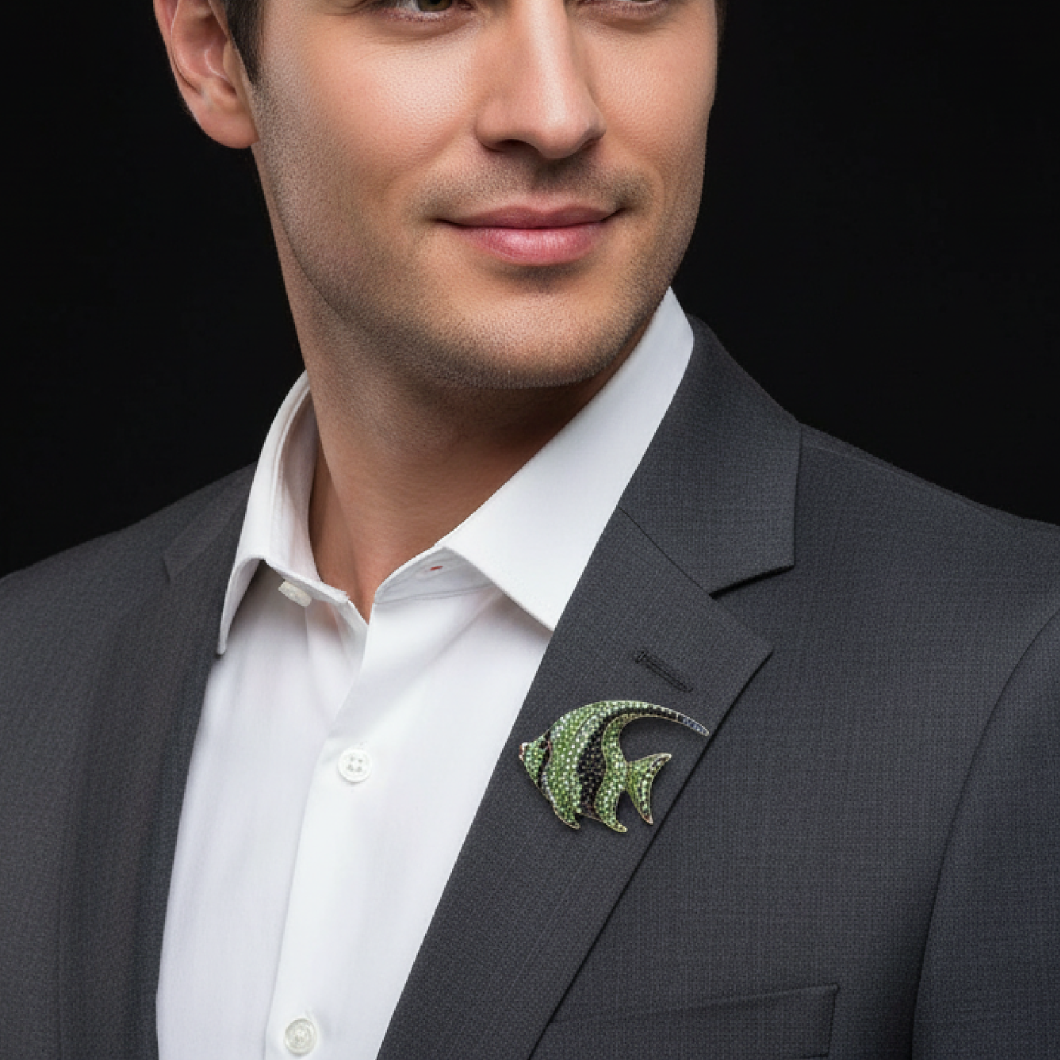 Man wearing a gray suit with a green fish-shaped brooch on a black background