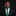 Man wearing a black suit with a green tie and blue pocket square on a black background