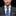 Man wearing a gray suit with a blue plaid tie and matching pocket square on a black background