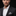 Man wearing a black suit with a white shirt and checkered pocket square on a black background