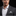 Man wearing a gray suit with a white shirt and patterned pocket square on a black background
