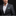 Man wearing a gray suit with a white shirt and patterned pocket square on a black background