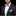 Man wearing a black suit with a white shirt, gray bow tie, and matching pocket square on a black background.