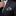 Man adjusting his tie with a plaid pocket square in a dark suit jacket.