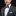 Man wearing a gray suit with a blue bow tie and pocket square on a black background