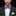 Man wearing a black suit with a patterned bow tie against a dark background