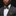 Man wearing a gray suit with a patterned bow tie and pocket square against a black background