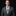 Man wearing a gray suit with a green and white checkered tie against a black background